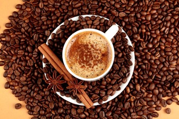 Cappuccino or latte surrounded by coffee beans and cinnamon