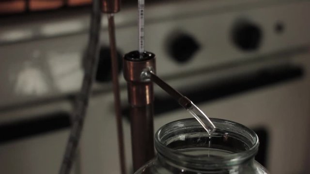 Alcohol distillation equipment, hooch fluid flow into glass jar