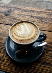 Hot Delicious Cappuccino Coffee served on blue cup on wooden table...