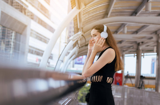Beautiful young woman using headphones and listening to music in the city