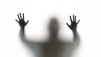 Silhouette of a zombie trying to get through a glass window. Great for Halloween.