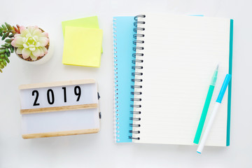 2019 on wood box, blank notebook paper on white marble table background, 2019 new year mock up, template with copy space for text, top view