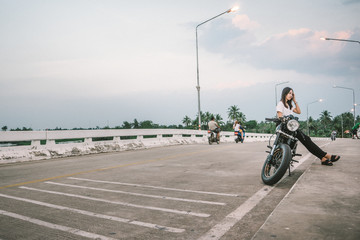 a women wearing a white shirt was sit on a back motorcycle and she smiling happily