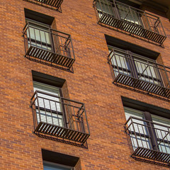 Fototapeta na wymiar High rise with narrow balconies and brick wall