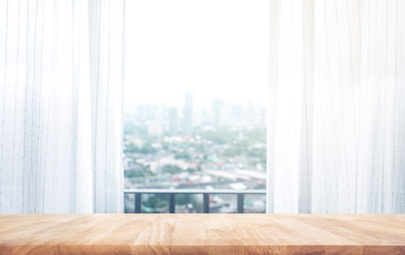 Wood table top on on blur of curtain with window city view background