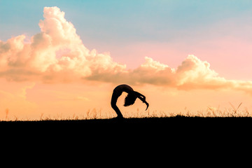 silhouette of children playing yoga on meadow at sunset time
