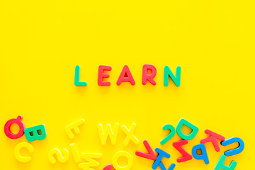 Fototapeta na wymiar Children learn read concept. Word learn written by plastic letters on yellow background top view copy space