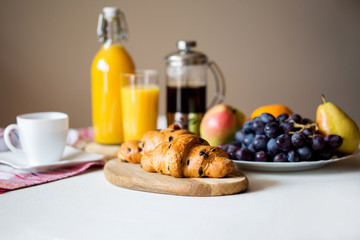 Breakfast with croissant. Orange juice in a glass bottle. Coffee in the French press. Good start to the day. Good morning.