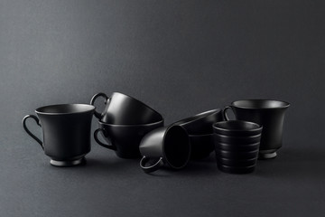 Total black / Creative concept photo of kitchenware, painted cups and mugs on black background.