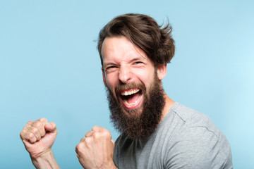 victory success and achievement. excited thrilled agitated guy making a winner gesture. hipster man...