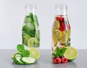 Home made detox water recipe, drinks in glass bottles with mint, lime, cucumber, raspberry.