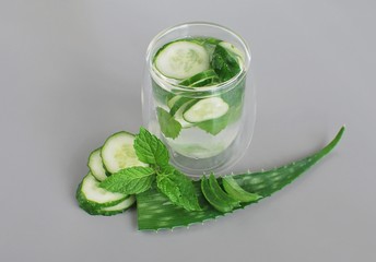 Home made infused detox drink for weight loss with aloe vera, cucumber and peppermint. Gray background, space for text.