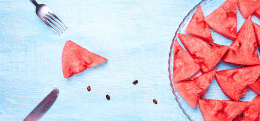 Watermelon slices on the glass plate on blue background. Top view, flat lay.