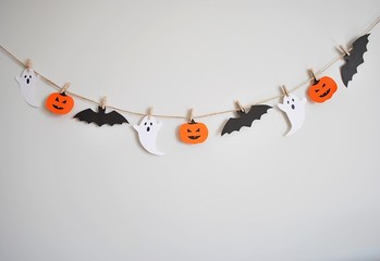Halloween paper garland with ghost, pumpkin and bat hanging on the wall. Easy crafts for kids.