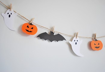 Halloween paper garland with ghost, pumpkin and bat hanging on the wall. Easy crafts for kids.