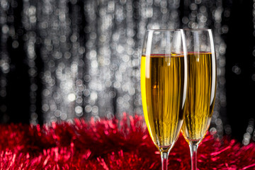 Two champagne or wine glasses with red and silver christmas tinsel decoration.