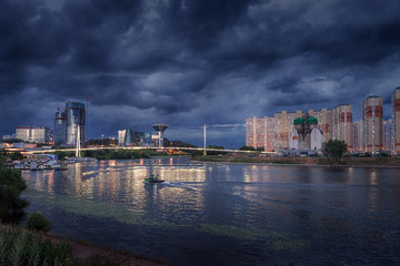 Fototapeta na wymiar Moscow region. July 02, 2018. Thunderous sky over the Moscow River The embankment. Pavshinsky Bridge. Crocus City Exhibition Complex and the Government House