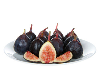 Fresh whole figs on an off white porcelain plate with sliced fig facing viewer, isolated on white...