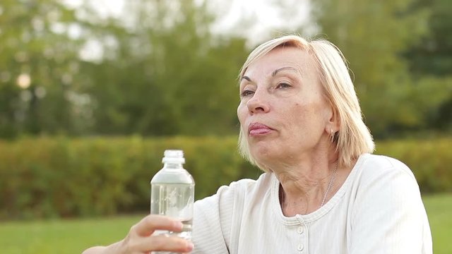 Mature woman drinks water, close-up