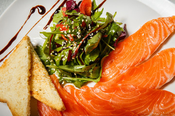 closeup rucola and tomato salad served with salmon slices and toasted bread