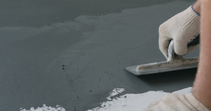 Closeup Male Worker Applying Micro Concrete Plaster Coating On The Floor With A Trowel