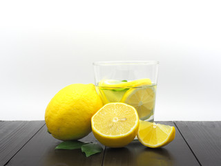 Fresh lemon juice in small bowl and lemon slice on dark wood background