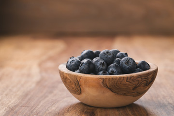 Fresh blueberries in wood bowl on table slightly toned