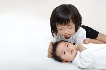 新生児の妹の顔を覗き込む3才の幼い姉。家族、姉妹、愛情、共生イメージ