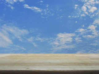 Empty brown wooden table top over blue sky with white clouds