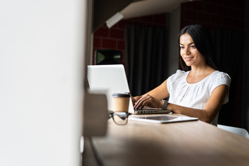 Searching for new solution. Pensive young beautiful businesswoman in glasses working on laptop while sitting at her working place