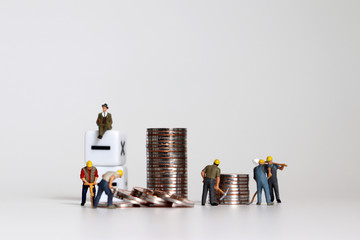 The concept of employment and labor costs. Miniature working people with piles of coins.