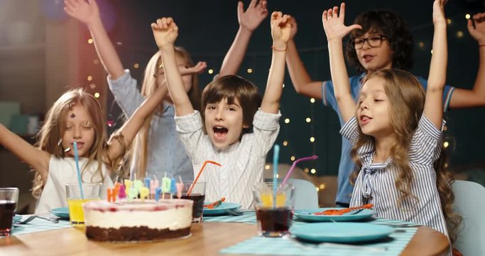 Children having birthday party. Group of kids celebraing birthday of their friend, cheering, having fun - happy childhood concept 4k