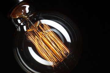 A classic Edison light bulb on dark background with space for text