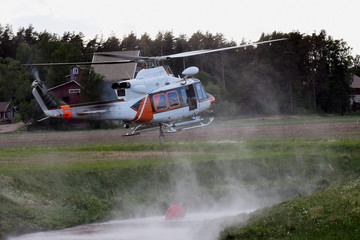 Aerial firefighting. Helicopter hovering over a small river to fill a bucket with water.