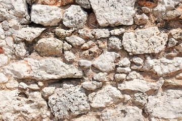Fragment of the old wall made of bricks, volcanic lava and limestone