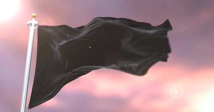 Black flag waving at wind in slow at sunset, loop