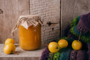 Homemade apple jam in bank in the autumn background with ripe apples and green leaves on the old wooden table, copy space