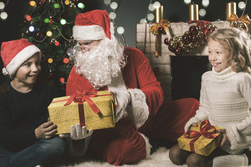Fototapeta na wymiar happy Santa Claus and children around the decorated Christmas tree