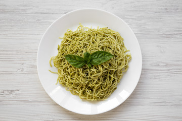 Plate of pasta spaghetti with pesto sauce on white wooden table, overhead. Top view, from above, flat lay.