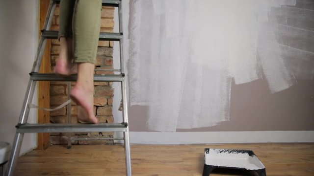 Home improvement. Beautiful woman painting wall with paint roller.