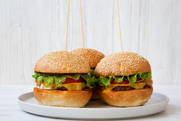 Cheeseburgers on grey plate on white wooden background. Side view. Close-up.