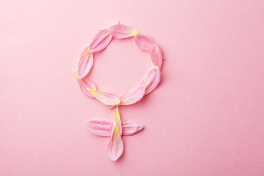 Gender Venus symbol made of beautiful flower petals on candy pink background, woman sign