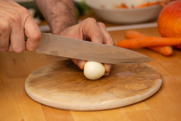 Man hands cutting an onion on a wooden board
