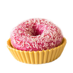Brightly pink donut on a white background in a yellow ceramic holder