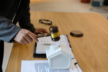 lawyer with judge gavel knocking house model with law document. real estate dispute & property auction concept
