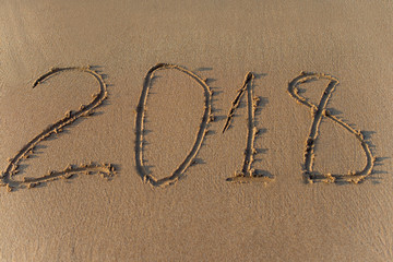 Year 2018 written on sand at sunset