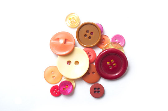 closeup of red and orange buttons and red cotton yarn on white background
