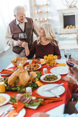 Obraz na płótnie Canvas senior couple clinking glasses of wine during thanksgiving celeration