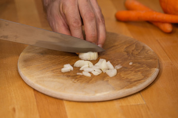 hands cutting onion on cutting board