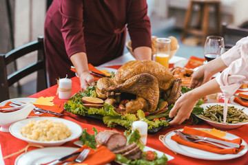 cropped shot of women serving tray wih turkey on thanksgiving table